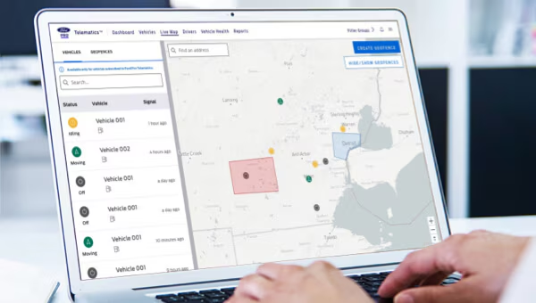 Fleet management software displayed on a laptop screen showing vehicle tracking on a map.