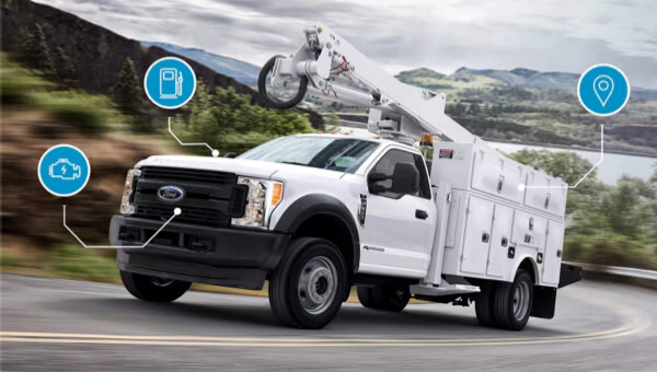 White utility truck with a mounted boom arm driving on a scenic road, featuring service icons.