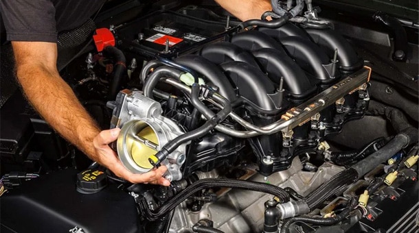 Mechanic adjusting a car engine throttle body, enhancing vehicle performance.