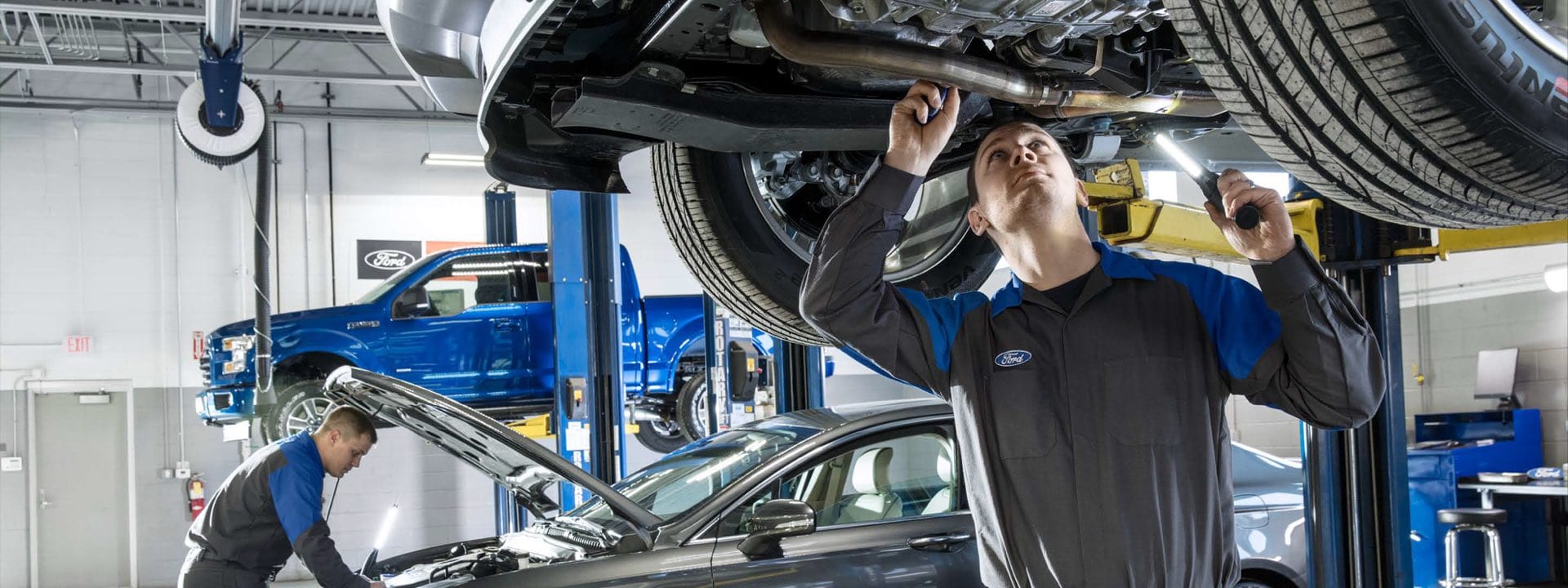 Mechanics inspect vehicles in a Ford service center, focusing on quality auto repair and maintenance.