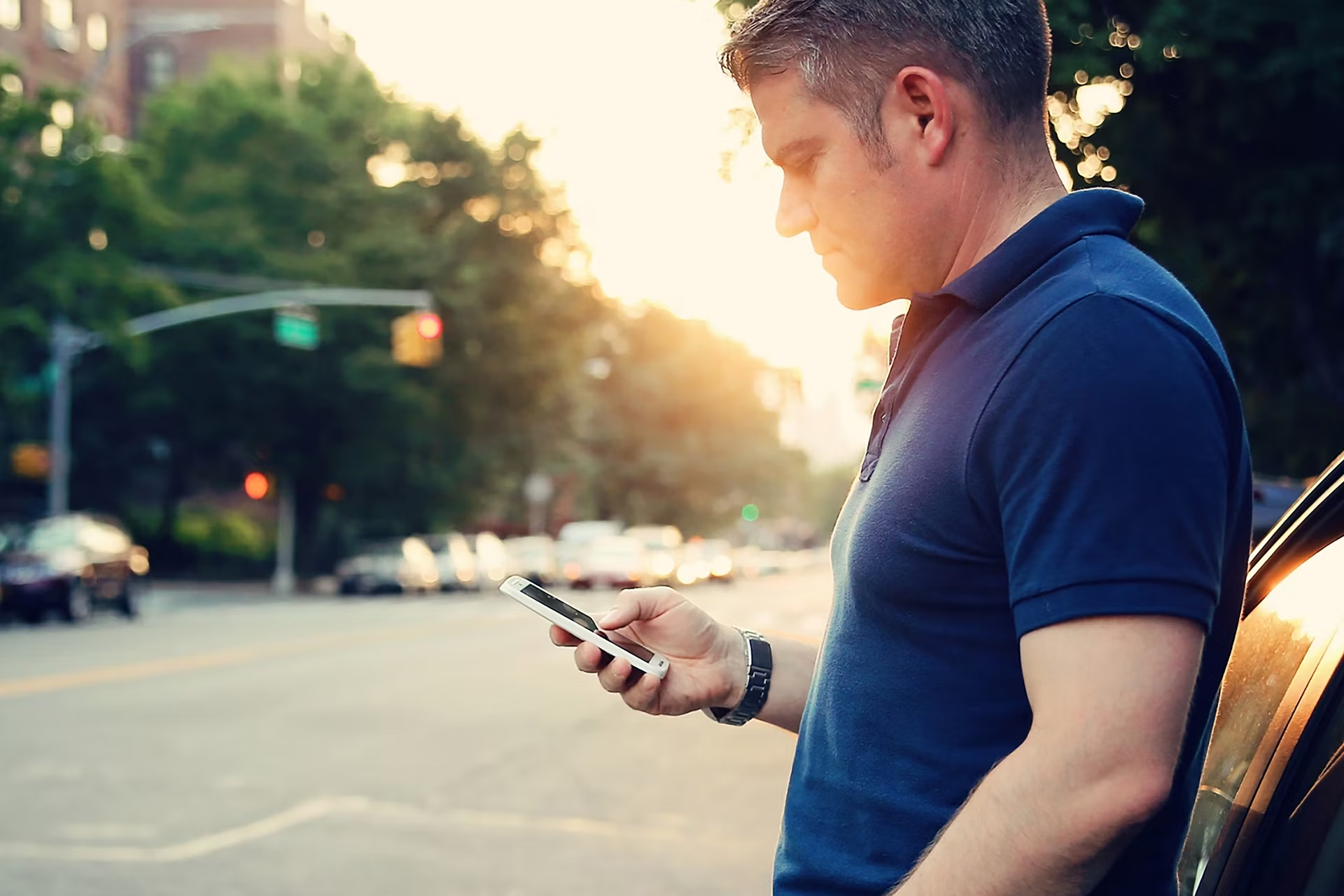 Young man using smartphone outdoors near a Ford car in Lakewest.